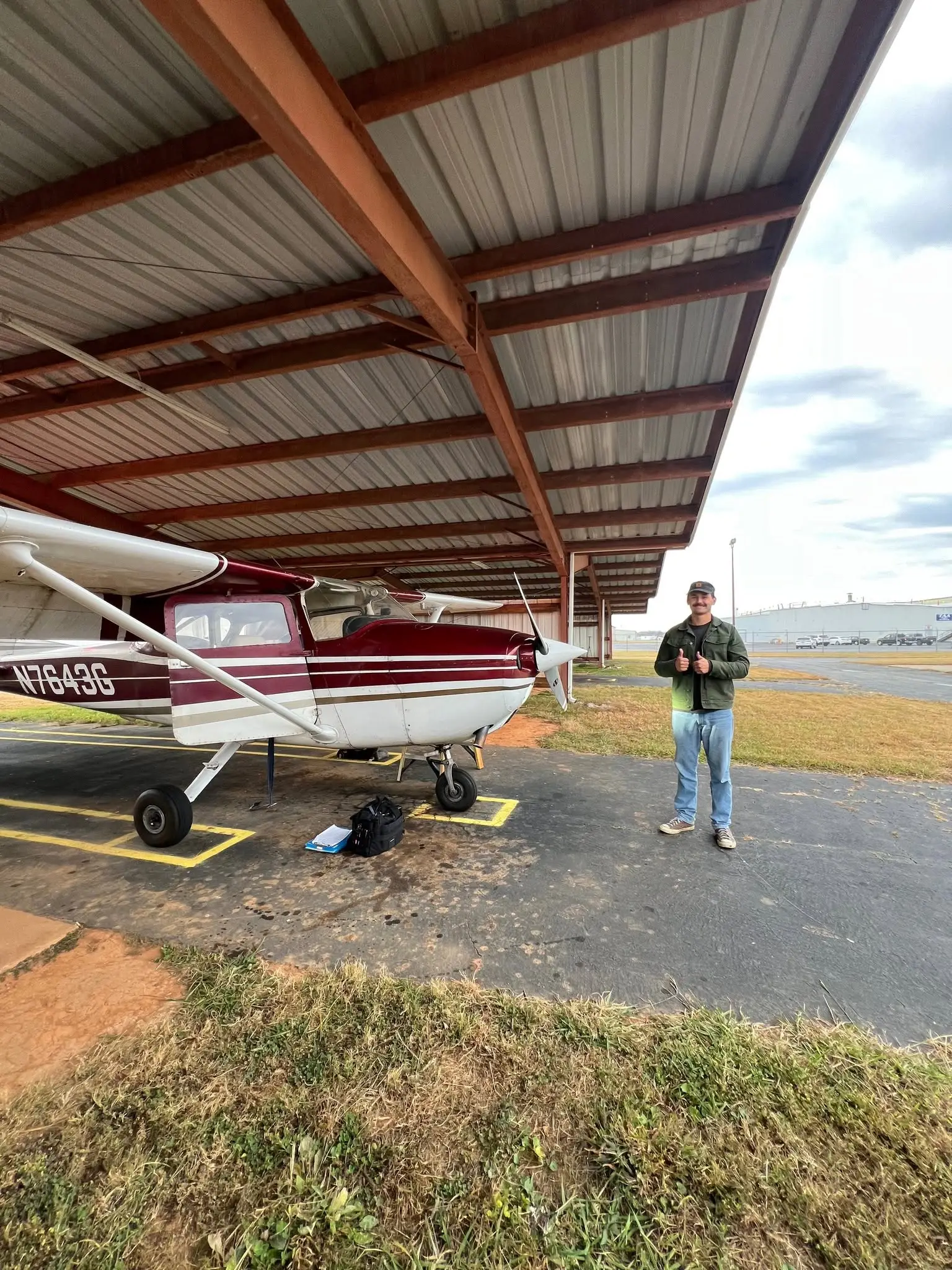 Student pilot giving thumbs up next to flight training Cessna