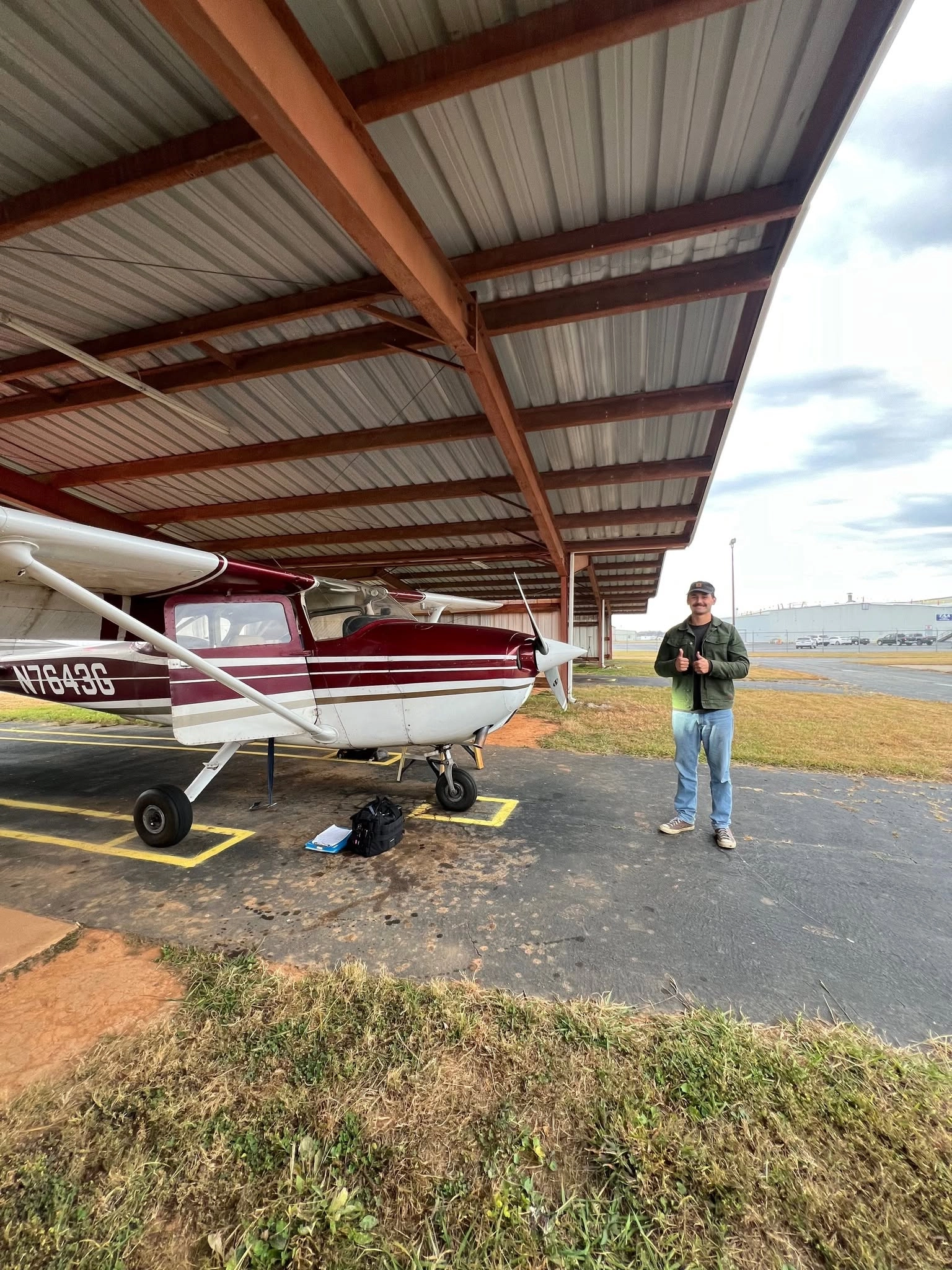 Student pilot giving thumbs up next to flight training Cessna