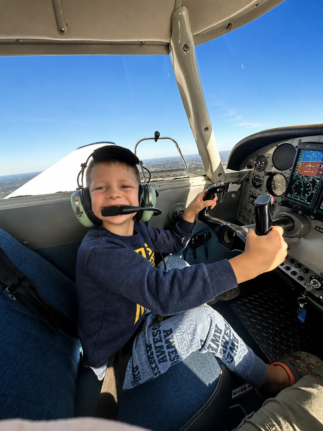 Young student pilot smiling while holding aircraft controls in cockpit